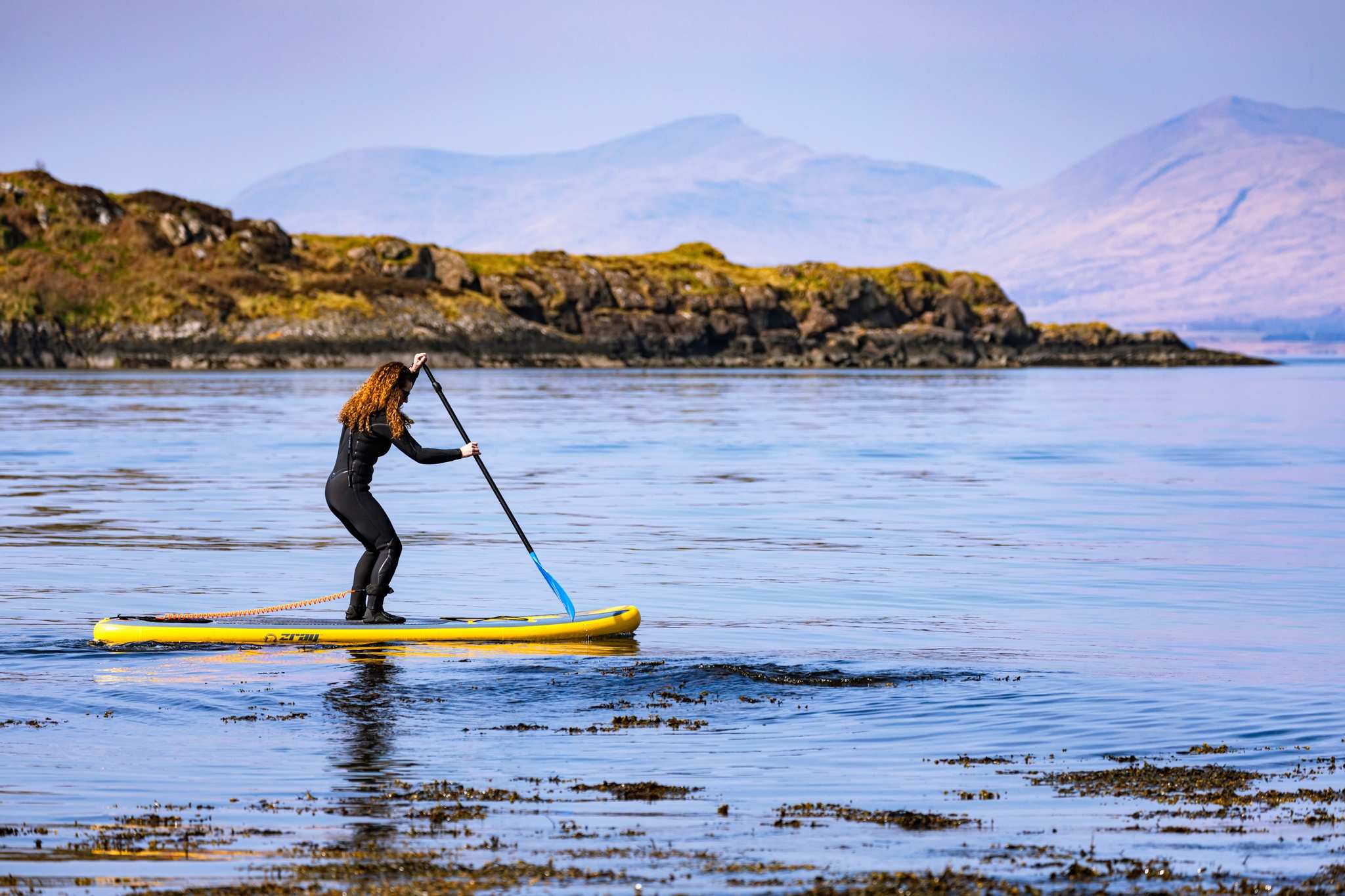 A group enjoy a Stand up paddleboarding lesson by Basking Shark Scotland at Ganavan Bay.